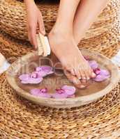 Softening her heels. Closeup of a woman scrubbing her feet.