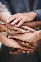 We pass our success from one to another. Shot of a group of businesspeople putting their hands together in unity.
