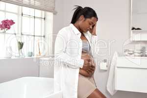 Getting through the challenges of pregnancy. Shot of a pregnant woman looking unwell at home.