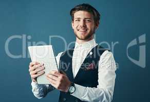 Technology keeps me ahead of the curve. Studio shot of a handsome young businessman using a tablet against a blue background.