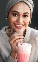 Decided to treat myself with a milkshake. Cropped portrait of an attractive young woman enjoying a milkshake at a cafe while wearing a headscarf.