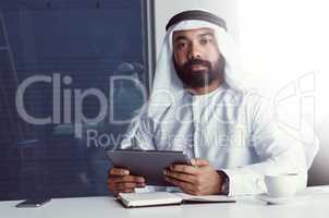 Partnering with technology to achieve success. Cropped portrait of a young businessman dressed in Islamic traditional clothing using a digital tablet while working in his office.