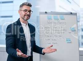 Welcome all to our weekly meeting. Shot of a mature businessman using a whiteboard during a presentation in an office.