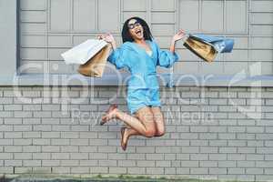 Shopping makes every girl leap for joy. Full length shot of an attractive young woman jumping for joy while holding shopping bags against a brick wall.