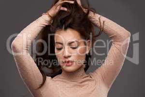 Confidence looks good on any face. Cropped shot of an attractive young woman posing in studio against a grey background.