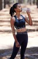 Replace all that sweat with water. Shot of an attractive young woman standing alone and drinking water during her workout outdoors.