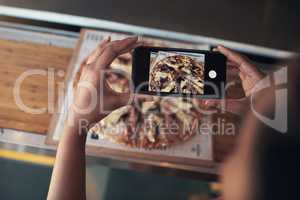 I have to put this on my blog. Cropped shot of an unrecognizable woman sitting alone and using her cellphone to photograph her pizza at a restaurant.