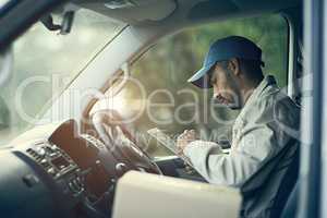 Scheduling his deliveries for the day. Cropped shot of a delivery man using a digital tablet while sitting in his van.