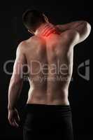 Struggling with a stiff neck. Studio shot of a sporty young man suffering with neck pain isolated on black.