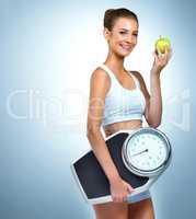 Less a diet, more a lifestyle. Portrait of a health-conscious young woman posing with an apple and a scale in studio.