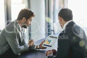 Looking for ways to increase profits. Shot of two colleagues looking at a graph on a digital tablet together in an office.