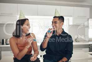 We feel like kids with our party horns. Shot of a young couple blowing party horns at home.