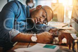 Hes passed the point of productivity. Shot of an exhausted young businessman sleeping at his desk in a modern office.