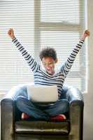 This is just the start of many more great things. Shot of a young woman looking at her laptop with her arms raised in celebration.