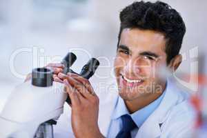 I think Im on to something.... Portrait of a smiling lab technician using a microscope while sitting in a lab.