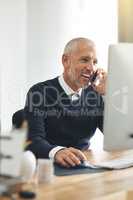 Of course Im available to talk. Cropped shot of a mature businessman talking on his cellphone while using a computer.