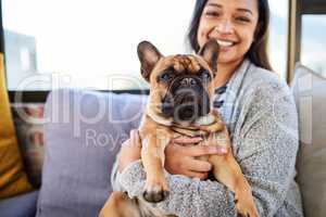 A house is not a home without a cute companion. Portrait of a young woman relaxing with her dog at home.