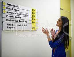 Which way should I go. Shot of an attractive young woman reading a directory on the wall of a medical center.