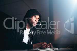 No code is uncrackable. Low angle shot of a young male hacker cracking a computer code in the dark.