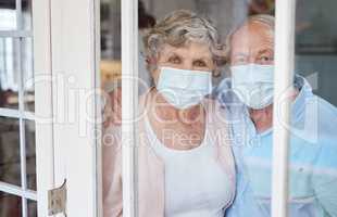 Love on an atom, love on a cloud. Portrait of a masked elderly couple at home in isolation together.