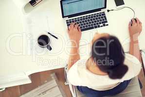 Shes prepared to work for her empire. High angle shot of a young businesswoman working on her laptop at home.