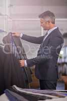 Youve got to dress for success. Shot of a mature businessman looking at a suit in a clothing store.