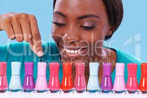 So many to choose from. A young african woman looking over a row of colorful nail polish.