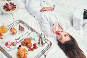 Im taking some time off to spoil myself. Shot of an attractive young woman enjoying a luxurious breakfast in her room.