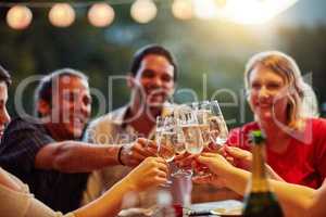 Good times are for celebrating with friends. Shot of a group of happy young friends toasting with champagne at a backyard dinner party.