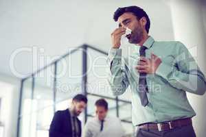 Feeling groggy with flu. Cropped shot of a businessman suffering with allergies in an office.