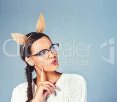 Dont think my rabbit ears cant hear what youre saying. Studio shot of a young woman wearing costume rabbit ears against a plain background.