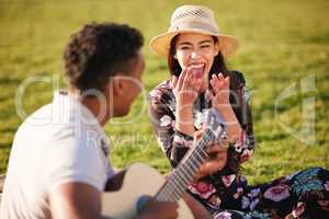 I saw that you were perfect, and so I loved you. Shot of a young man playing a guitar while on a picnic with his girlfriend at a lakeside.