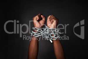 I want to break free. Cropped shot of a mans hands tied up with chains against a black background.