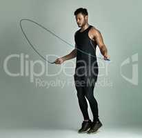 Best cardio workout ever. Studio shot of a young man skipping with a jump rope against a gray background.