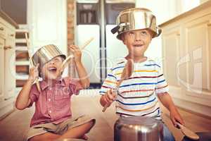 Lets get this party started. Two young boys sitting on the kitchen floor playing with pots and pans.