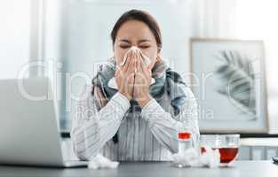 2020, the year the world went on sick leave. Shot of a young businesswoman blowing her nose at her desk in a modern office.