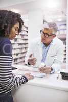 Just take these twice a day. Shot of a dedicated mature male pharmacist giving a customer prescription meds over the counter.