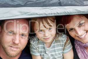 Escaping to the great outdoors as a family. Portrait of a cute little girl and her parents sitting inside a tent together.