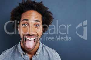Cant hide the excitement. Portrait of a happy young man sticking his tongue out on a gray background.