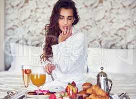 This looks good. Shot of an attractive young woman enjoying a luxurious breakfast in her room.