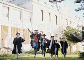 Running straight towards their dreams. Shot of a group of students running together in a row on graduation day.
