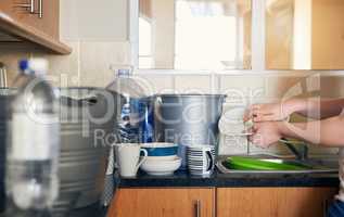 Another great way to save water. Cropped shot of an unrecognizable woman doing dishes and trying to save water in the kitchen at home.