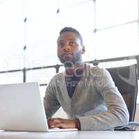 Dont just dream about it - go ahead and achieve it. Shot of a young businessman looking thoughtful while working on a laptop in an office.