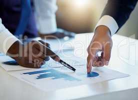 Maximising profits and eliminating loses. Shot of two unrecognisable businessmen going through paperwork in an office.