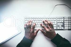 Fastest fingers on the web. High angle shot of an unrecognizable man typing on a keyboard while working late in the office.