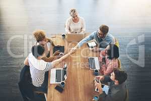 Building partnerships to increase productivity. High angle shot of businesspeople shaking hands during a meeting in an office.