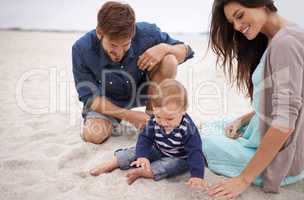 Nurturing his curiosity about nature. Cropped shot of a young couple and their baby boy sitting on the beach.