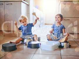 Lets make some noise. Shot of two adorable children playing on a drum set made of pots on the kitchen floor.