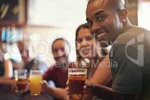 Glad you could join us. Portrait of a smiling young man in a bar with some friends.