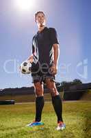 The games hero. Shot of a young footballer standing on a field with a ball in his hands.